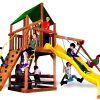 Children playing on a premium cedar wooden swing set in a landscaped backyard on a sunny day.